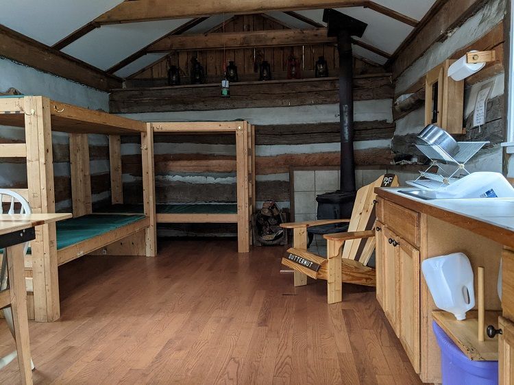 The interior of Wineberry cabin shows multiple bunks, a small kitchen, and a wooden chair.