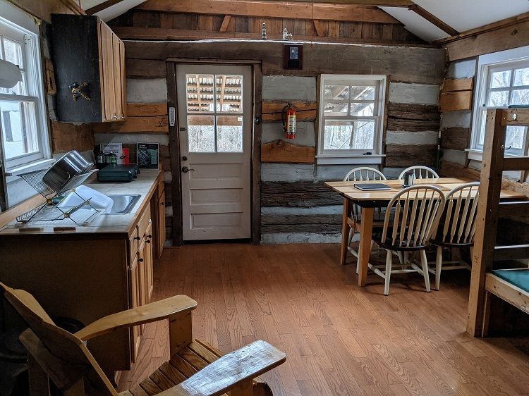 The interior view of Butternut cabin showing a small kitchen, with a wooden table and chairs. 