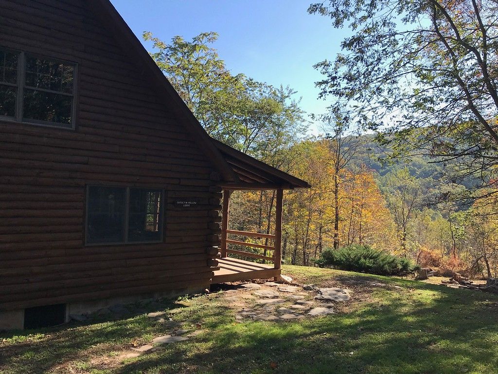 The side view of Catoctin Hollow Lodge shows a small wooden porch and a view of trees.