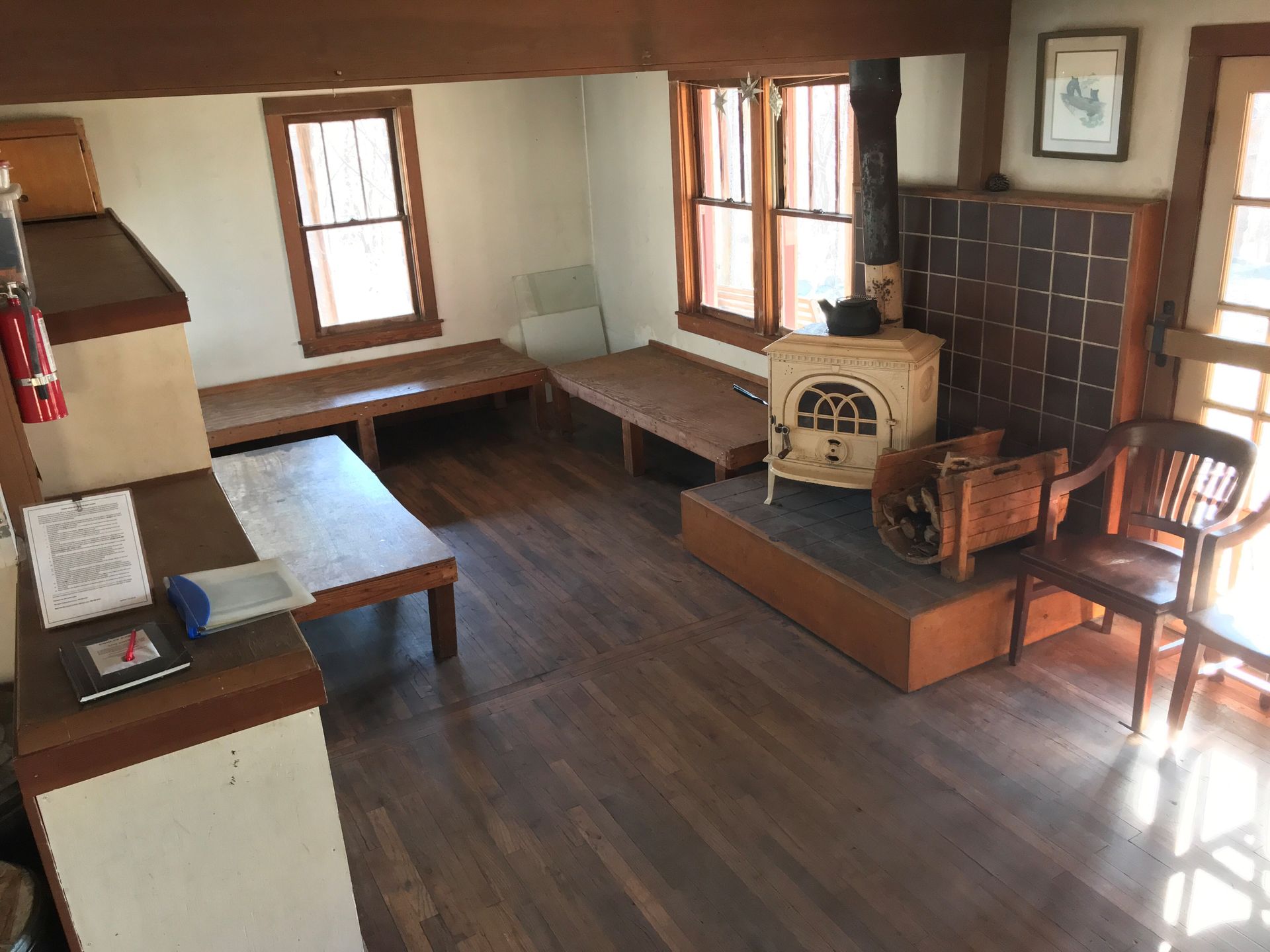 The interior of Conley cabin features multiple platforms to sleep on, a small fire place, and wooden chairs.