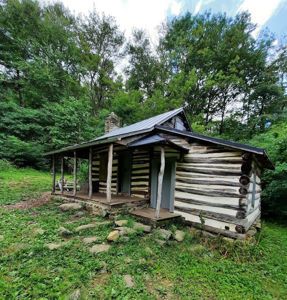 The front of the Corbin cabin shows a small porch and a wooden picnic table.