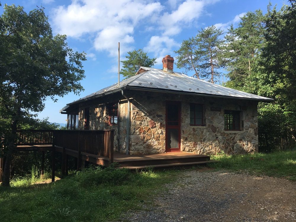 The front view of Glass House cabin shows a wooden porch.