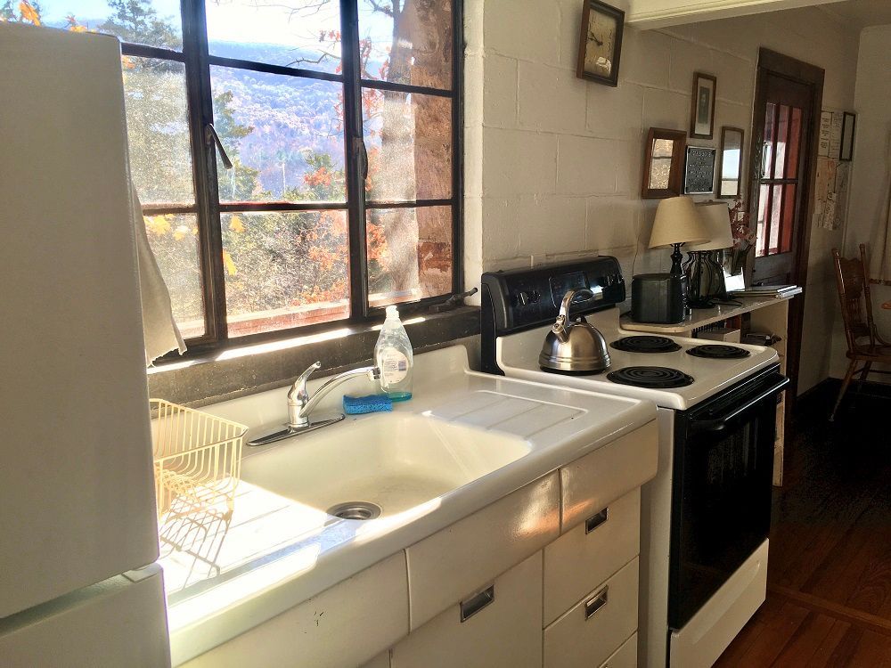 The inside of Glass House cabin shows a sink, stove top, and a small kitchen counter.