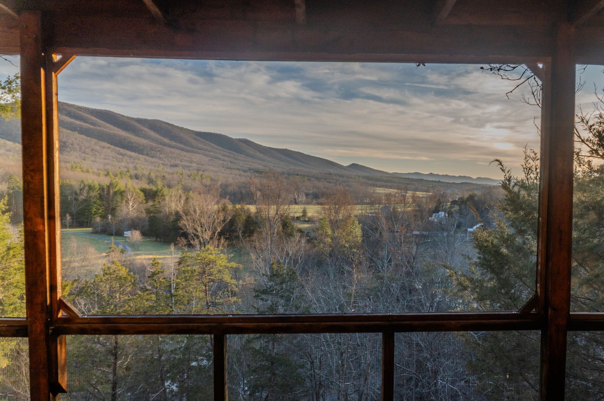 A small stone house with a wooden deck in the woods