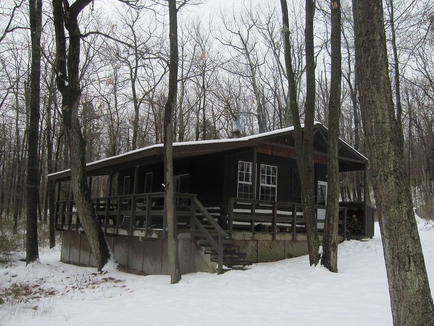 The Gypsy Spring cabin with a wooden porch, pictured in the snow.