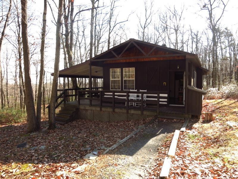 The front view of the Gypsy Spring cabin, featuring wooden chairs and a wooden rail guard.