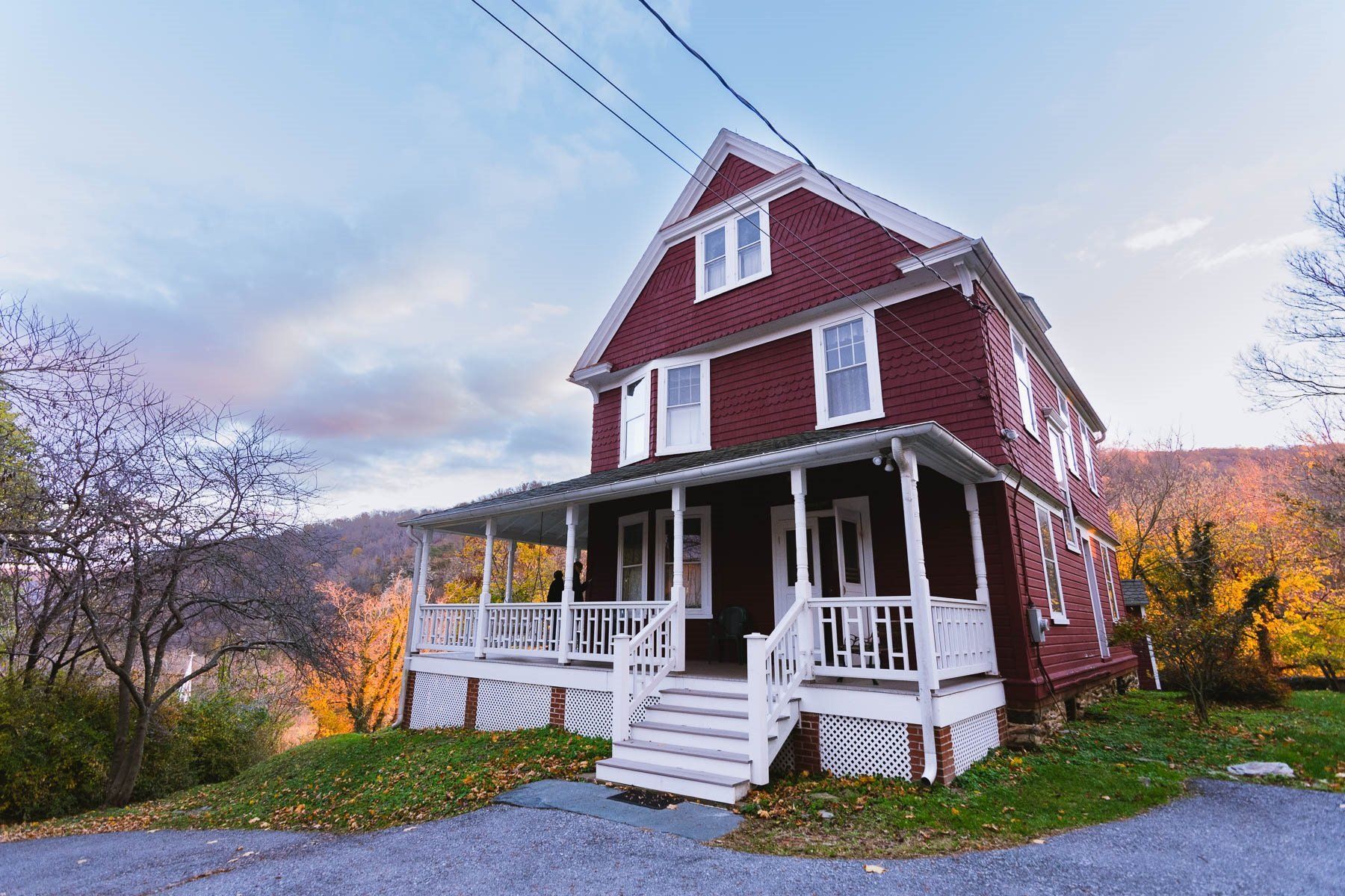 A large red house with a white porch is surrounded by trees.