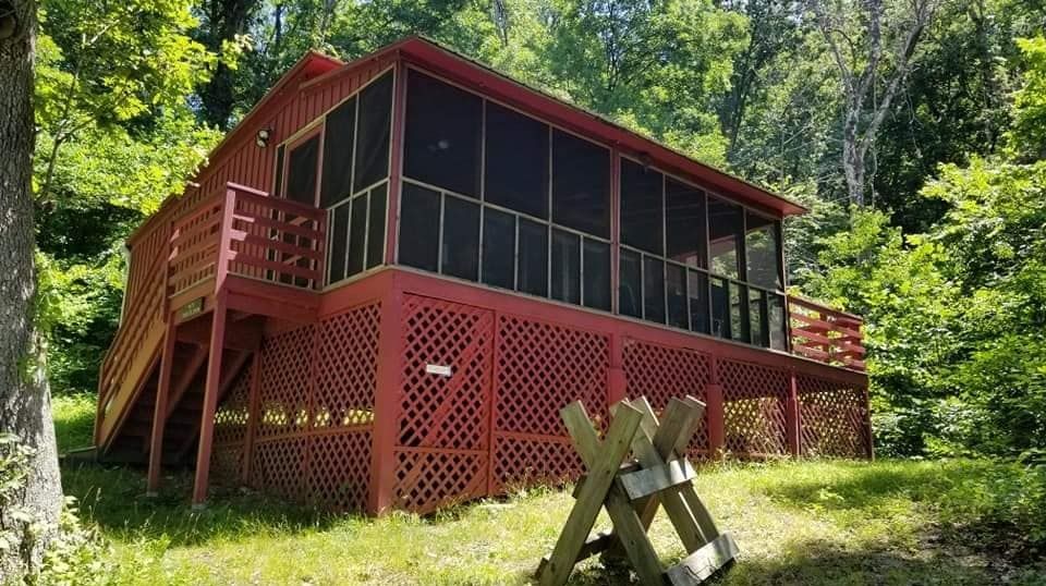 An exterior view of the Horwitz cabin, showing a red screened-in porch and wooden staircase.