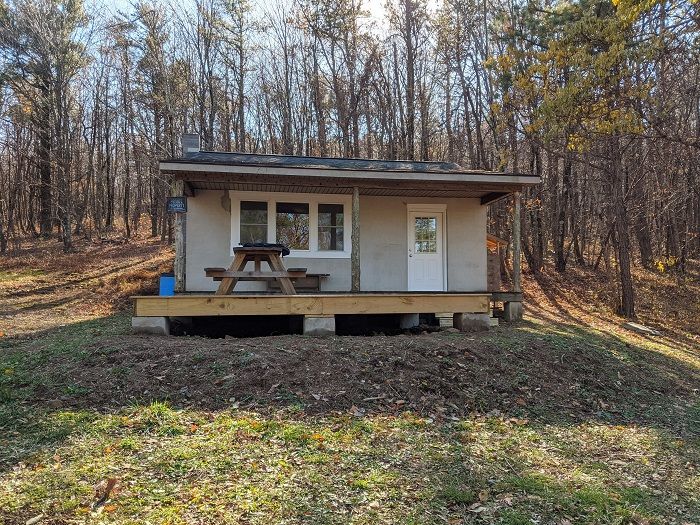 The back of the Jarmans Gap cabin shows a wooden platform with a wooden picnic table.
