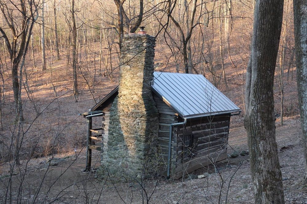 The rear of the Jones Mountain cabin shows a stone chimney and surrounding trees.