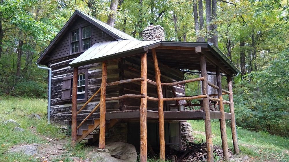 The front view of the Jones Mountain cabin showing an elevated wooden porch with chairs and benches.