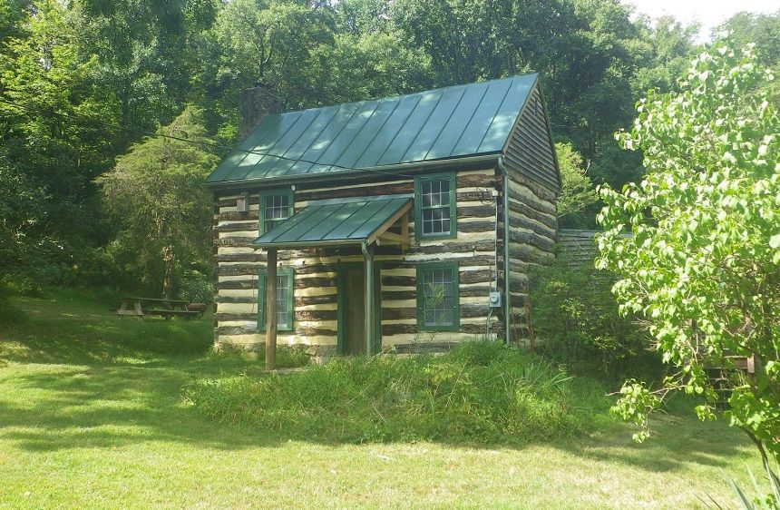 An exterior view of the Lambert cabin, surrounded by vegetation and featuring a picnic table.