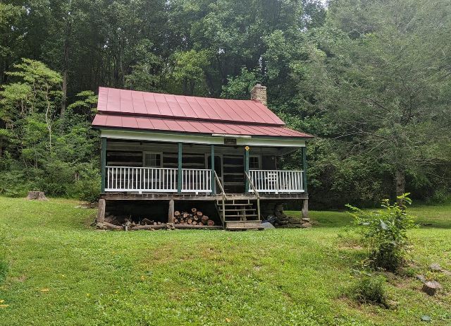 A view of the Meadows cabin showing a wooden porch and firewood.