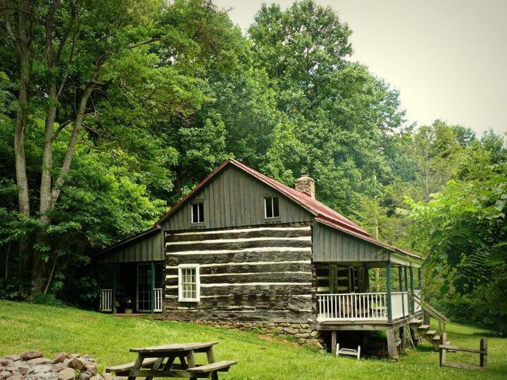 An exterior view of the Meadows cabin showing a porch and multiple wooden picnic tables.