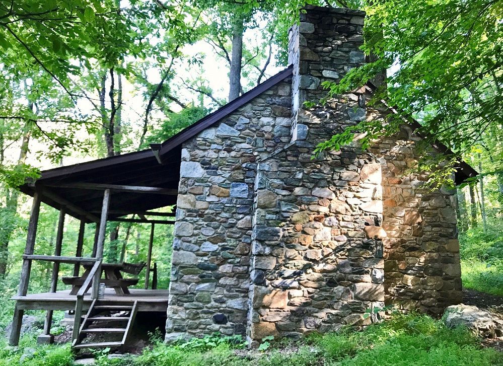 The side view of Myron Glaser cabin shows a wooden porch and a stone chimney.