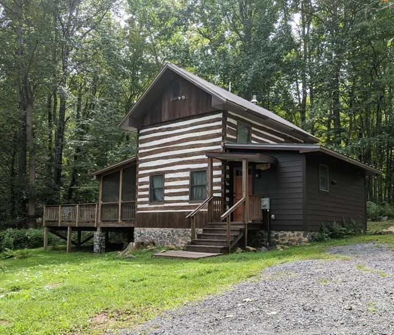 An exterior view of the Old Rag cabin showing wooden steps leading up to a wooden porch.