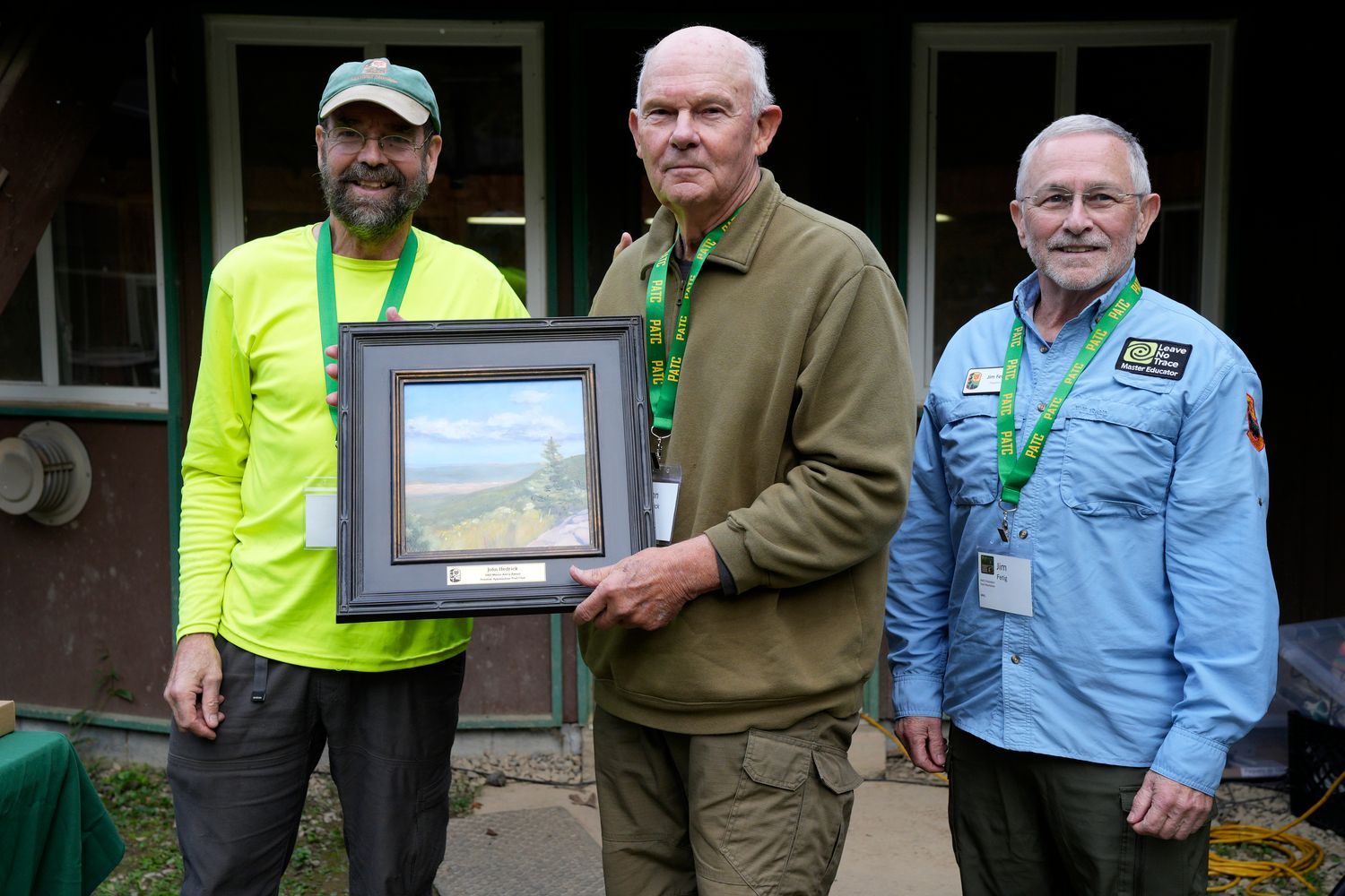 Two men are standing next to each other in a room holding a painting.