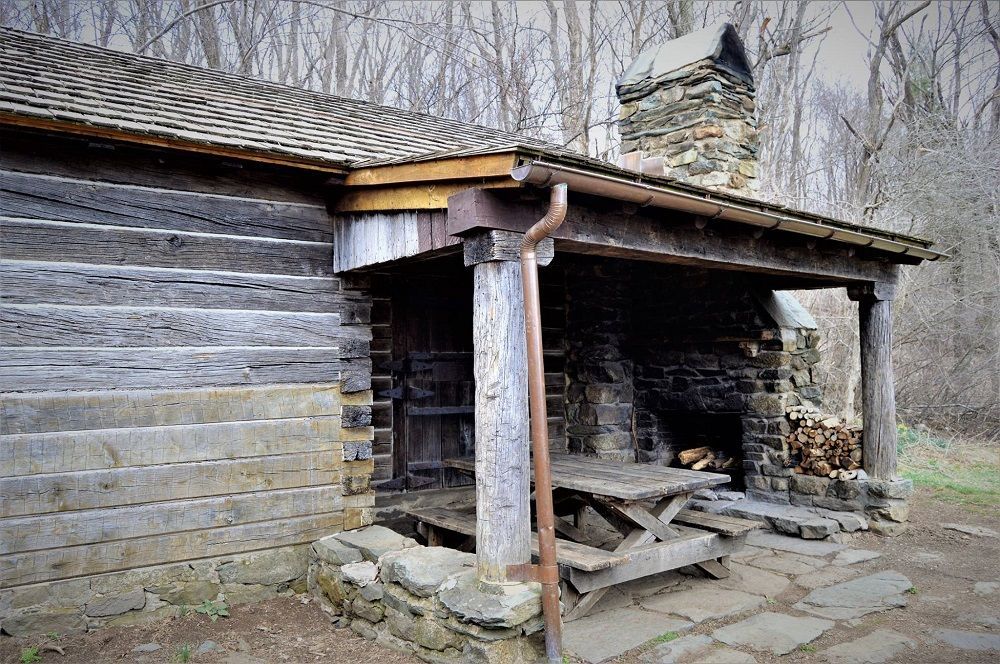 The porch of the Pocosin cabin features a wooden picnic table and a fireplace.