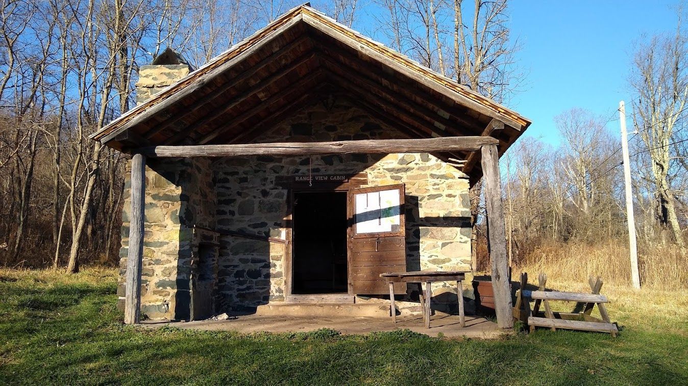 The front of the Range View cabin shows a small porch and a wooden table.