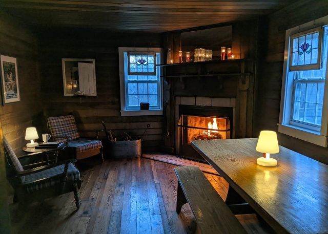 The inside of Rosser Lamb cabin shows a fire place, chairs, and a wooden table with benches.
