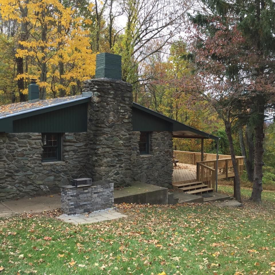The side view of the Schairer Trail Center cabin, showing stone side paneling and a wooden front porch.