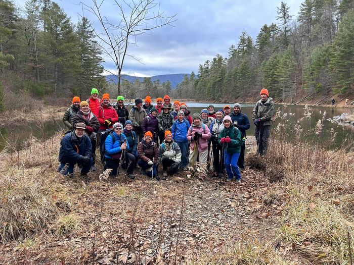A group of people are posing for a picture in the woods near a lake.