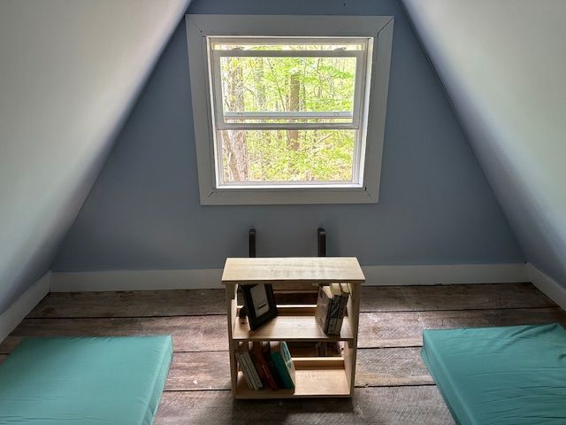 The interior of Tulip Tree cabin shows a wooden table with multiple wooden chairs, and a stone fireplace with a wood burning stove.