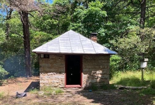 The front view of Sugar Knob cabin, made of stone and has a metal roof.