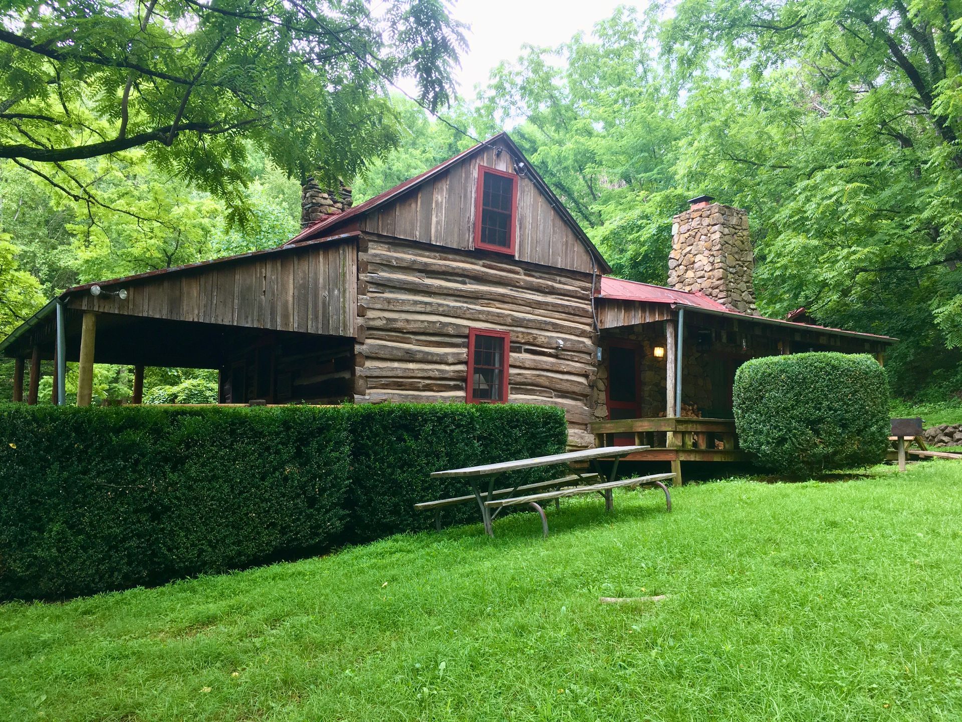 The front view of Vining cabin showing two porches and a wooden picnic table in the grass.
