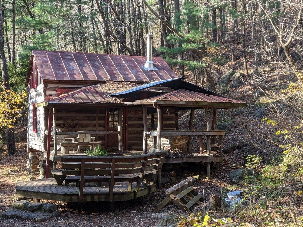 The front view of Wineberry cabin showing a front porch and additional seating area, with wooden chairs and benches.