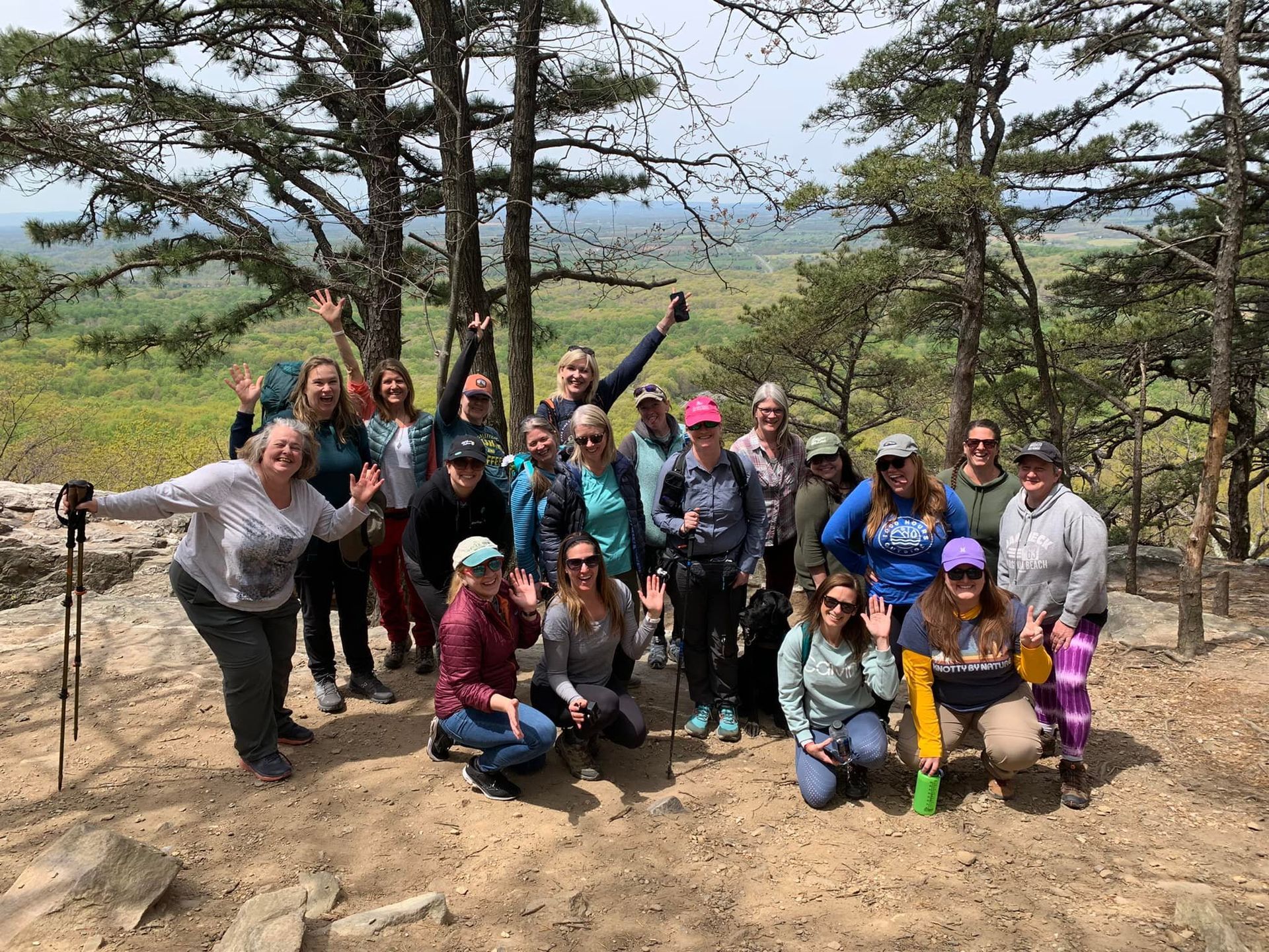 A group of female hikers posing together for a photo, on top of a summit in the mountains.