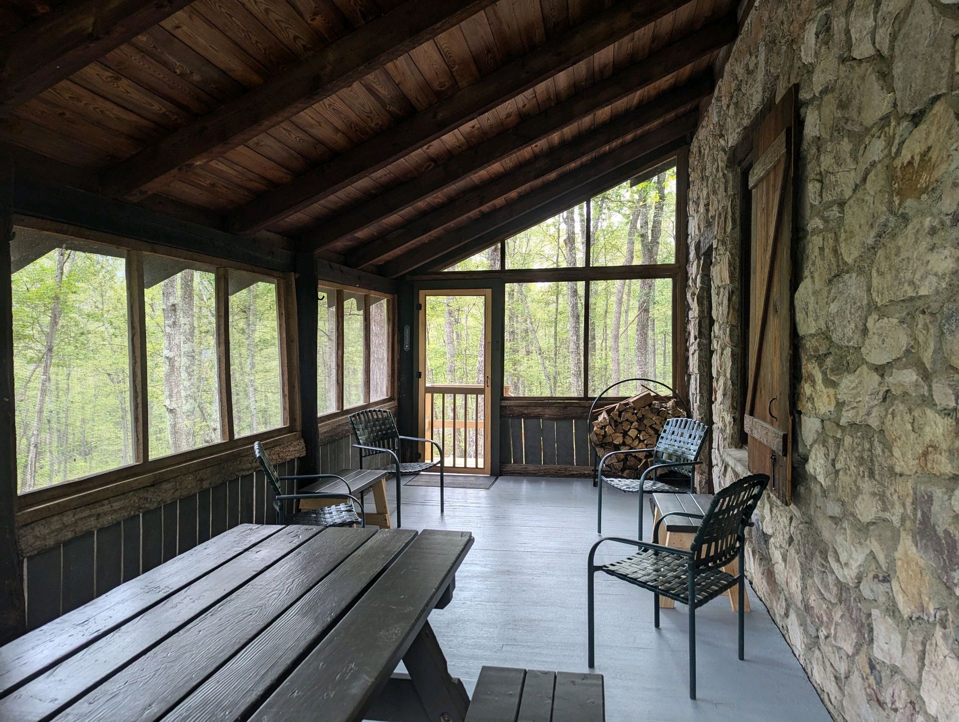 The cook-shed at Tulip Tree Cabin shows a fire pit, a wooden picnic table, and a wooden counter to cook on.