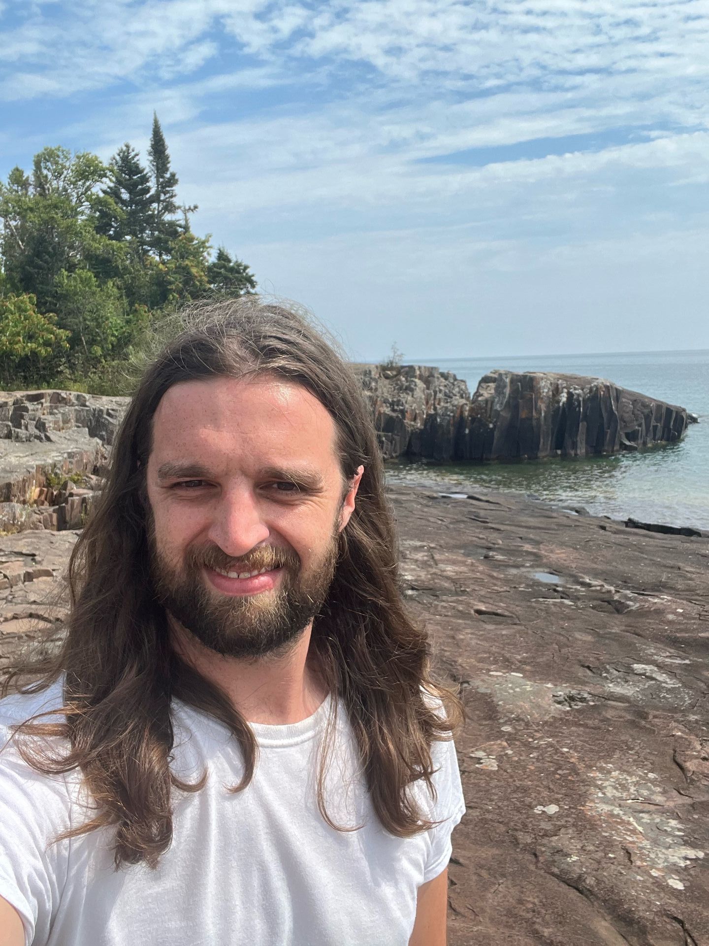 Rush standing on a rocky summit wearing a dark plaid shirt