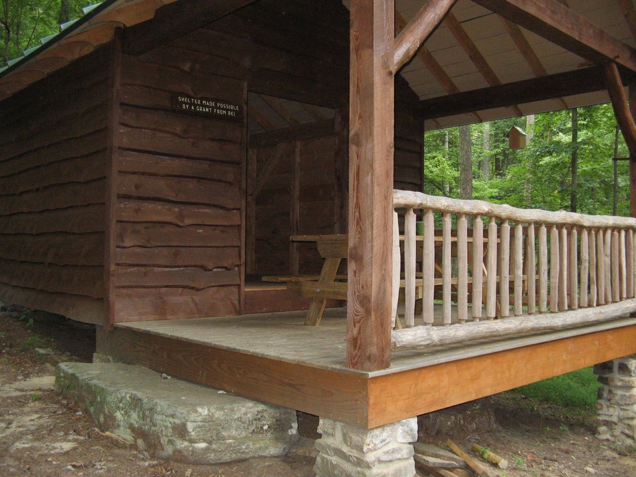 A wooden PATC shelter, with a porch and picnic table.