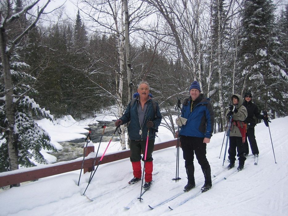 A group of PATC Ski Touring members, skiing along a snowy path, in the forest.