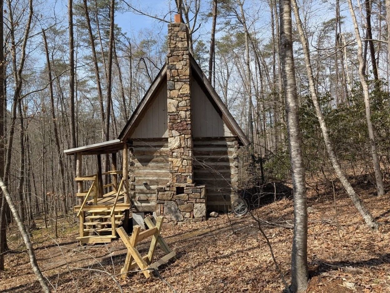 A living room in a log cabin with a couch , table and chairs.