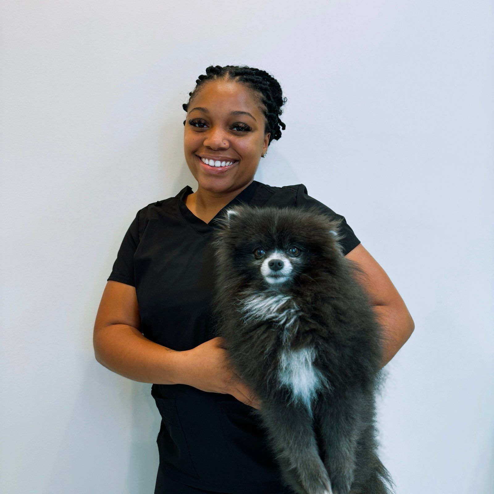 A woman in a black shirt is holding a small black dog