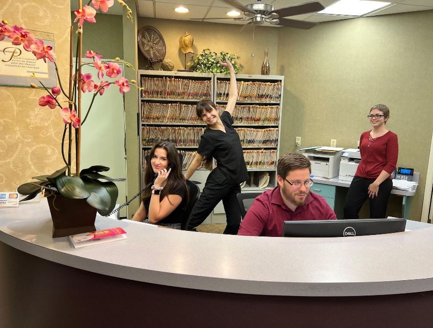 A group of people are sitting at a desk in a dental office.