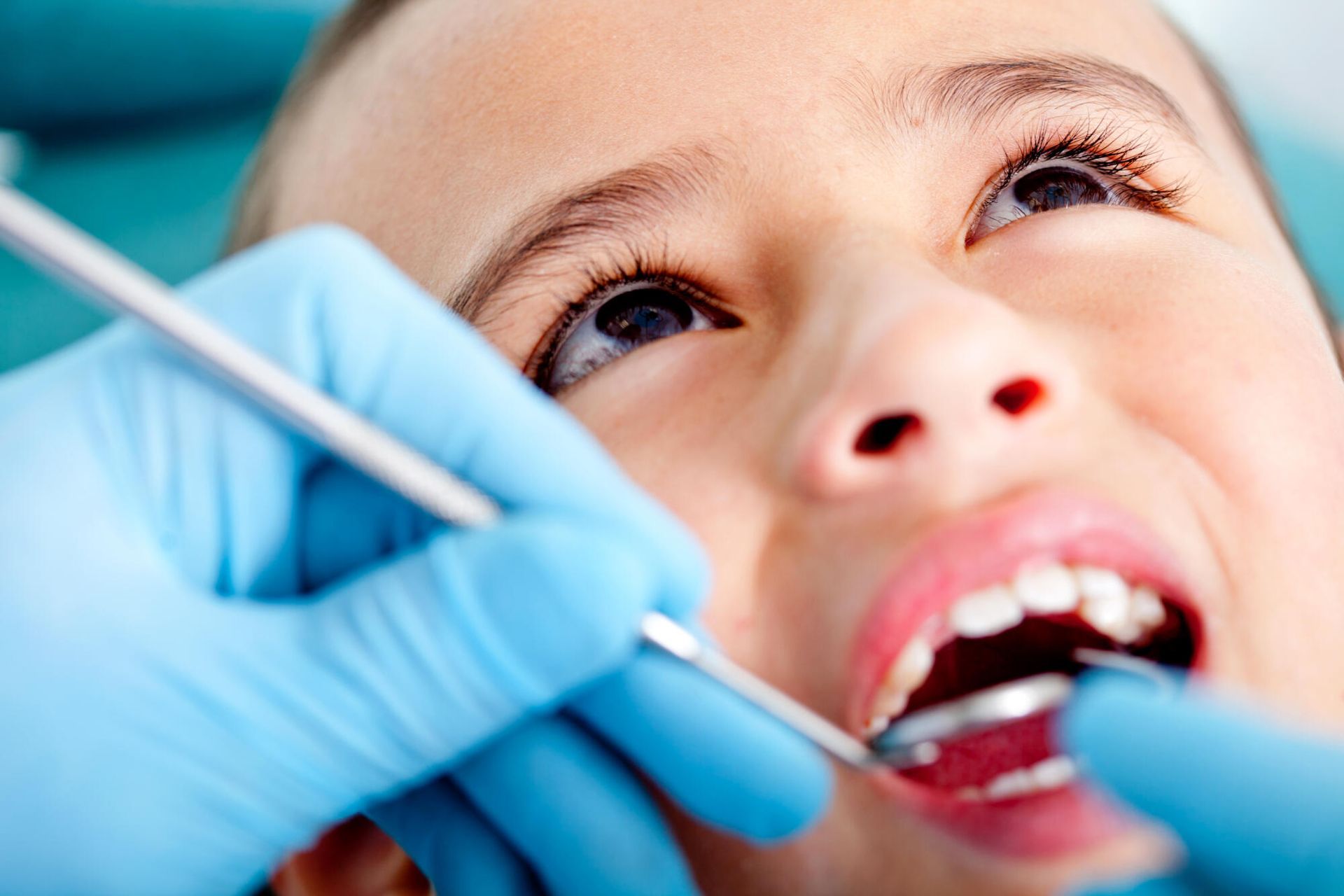 A young girl is getting her teeth examined by a dentist.