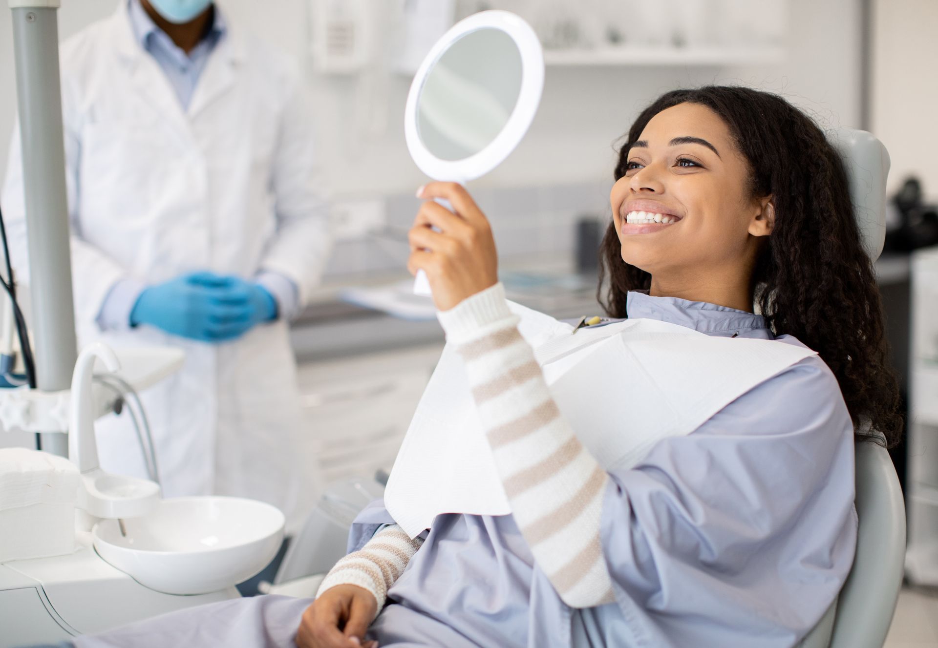 Patient smiling at her reflection in a mirror after dental treatment at Clearwater Dentist