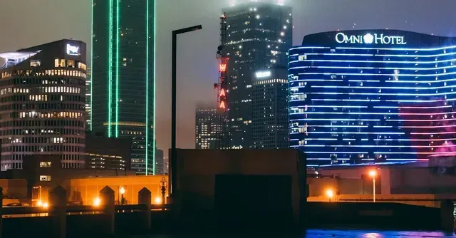 A city skyline at night with a hotel in the foreground.