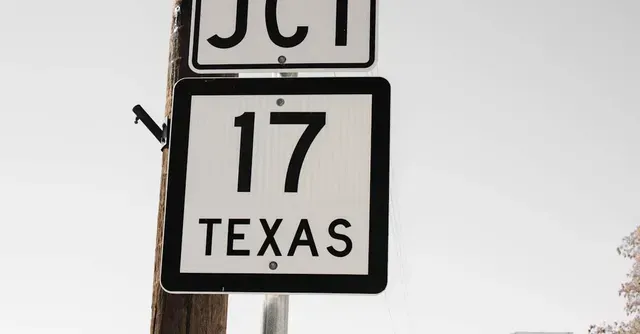 A speed limit sign for texas is hanging on a pole.