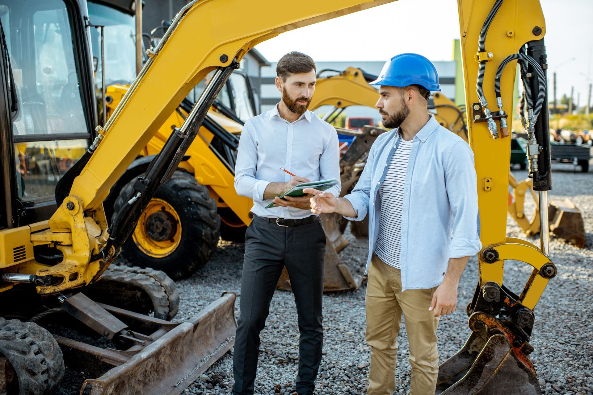 Two men are standing next to a bulldozer on a construction site.