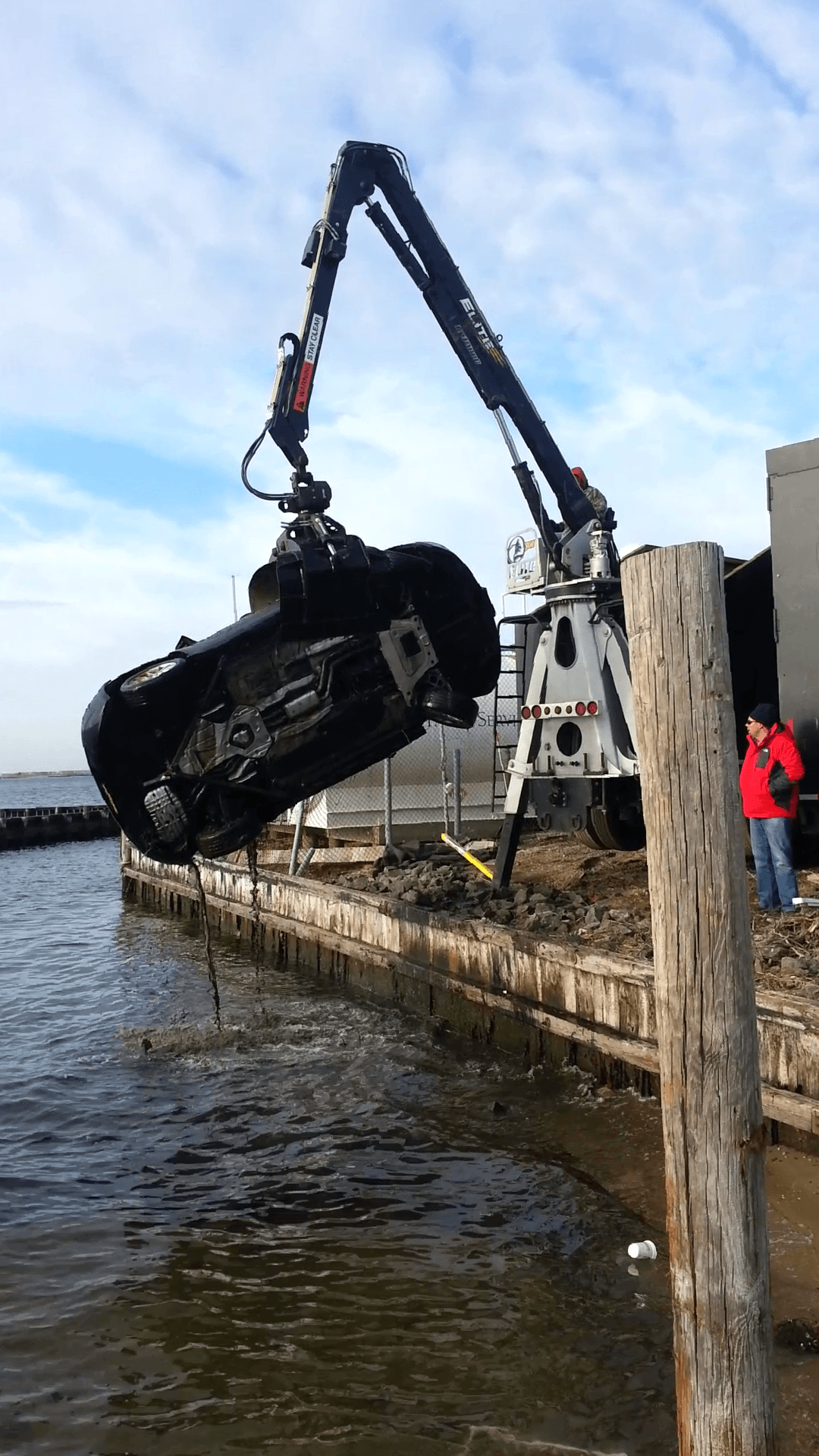 A car is being lifted out of the water by a crane.