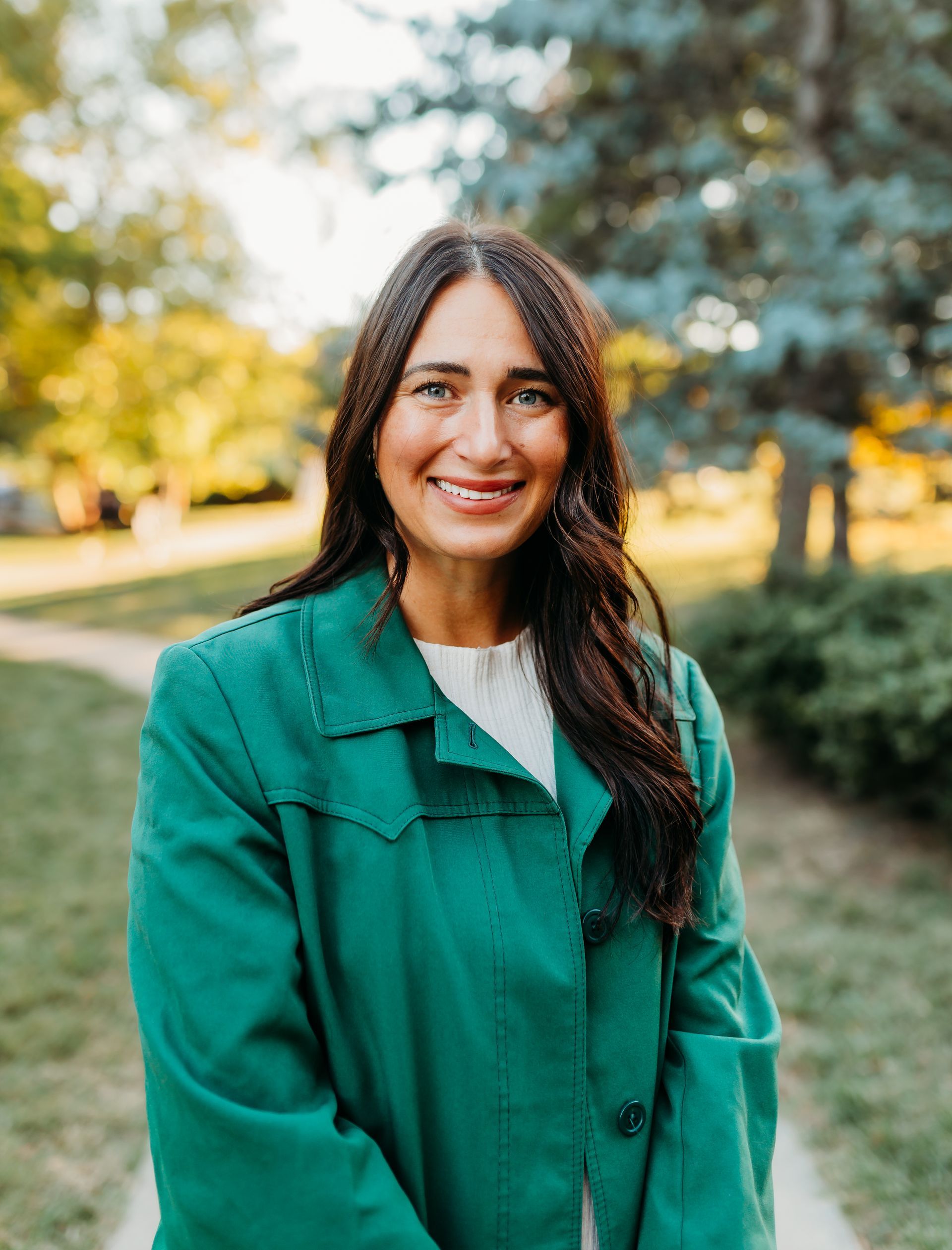 A woman in a white blouse and blue jeans is walking down a sidewalk.