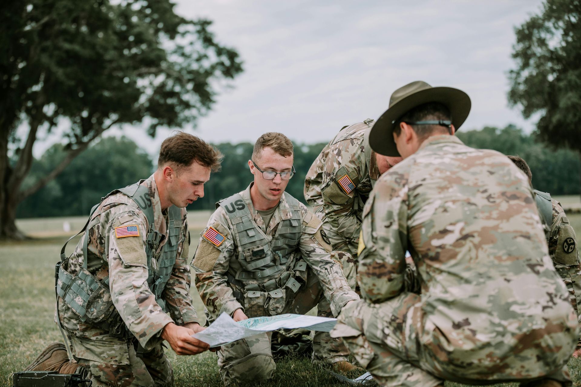 A group of soldiers are looking at a map in a field.