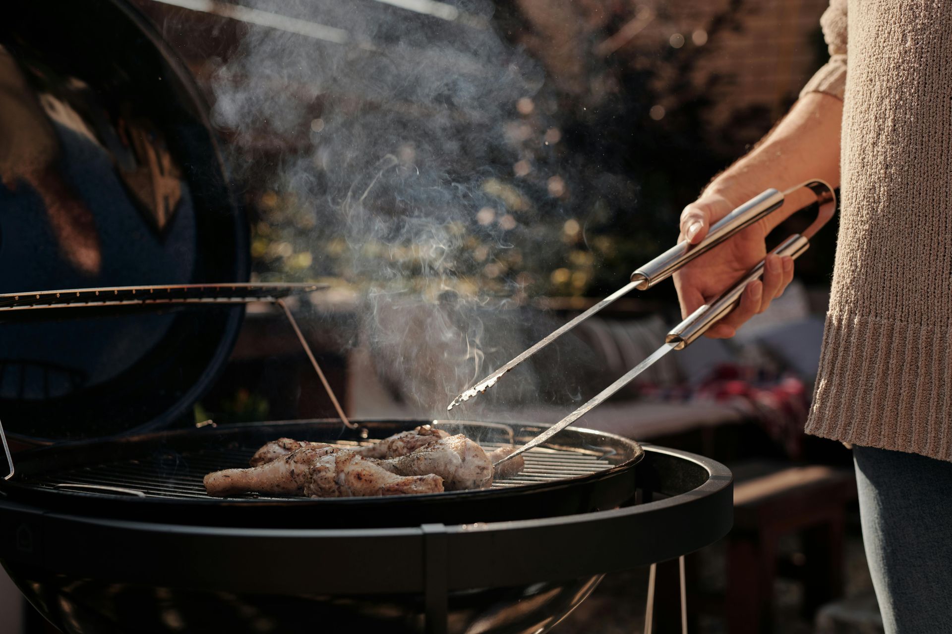 A person is grilling meat on a grill with tongs.