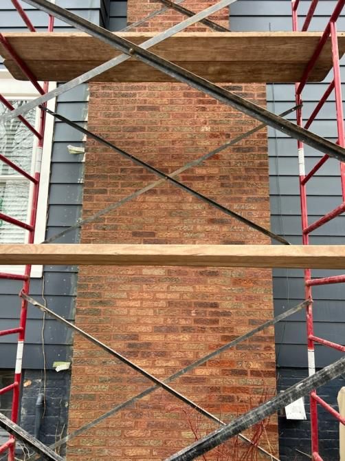 A brick chimney is being repaired on the side of a building.