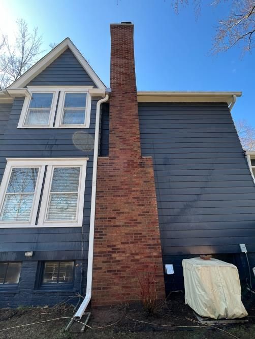 A large brick chimney is on the side of a house.