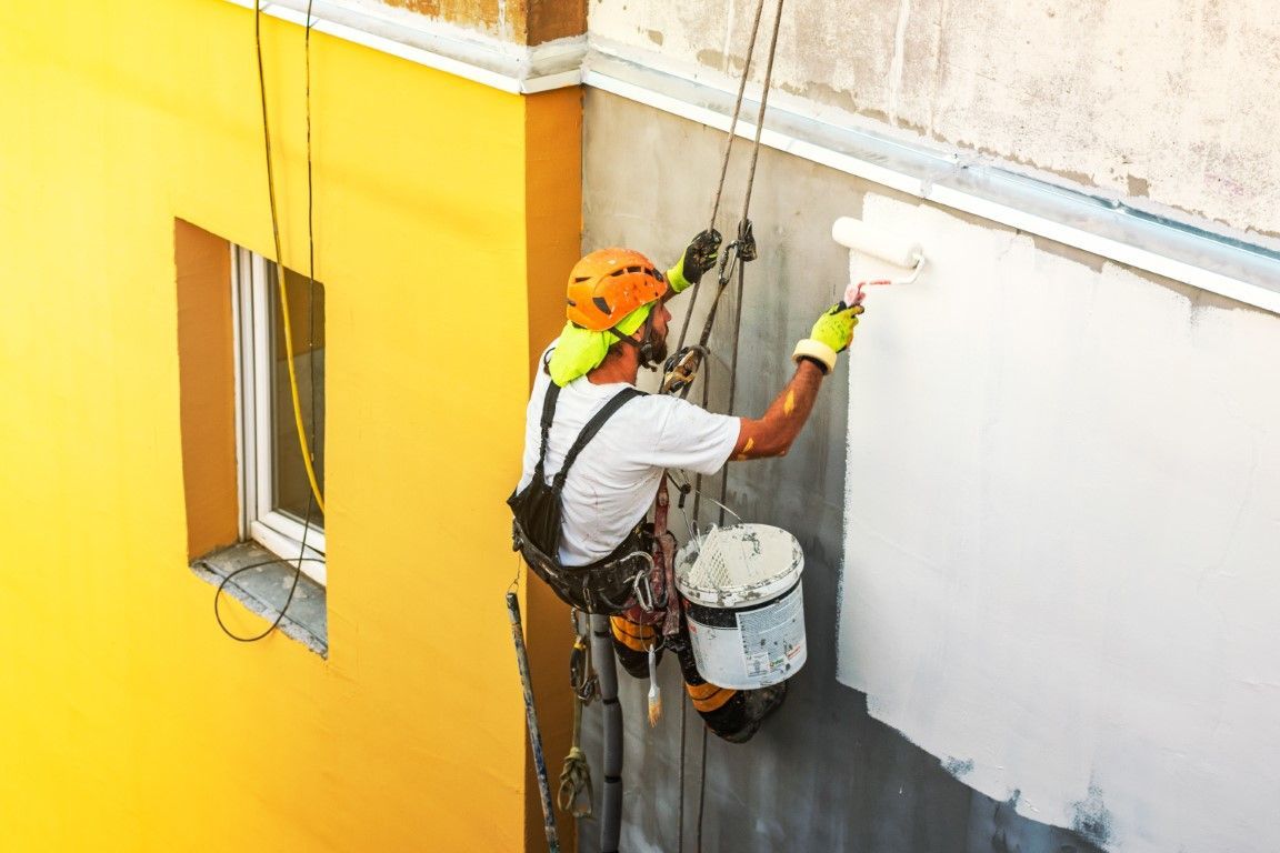 Team of commercial painters on ladders painting a large building.